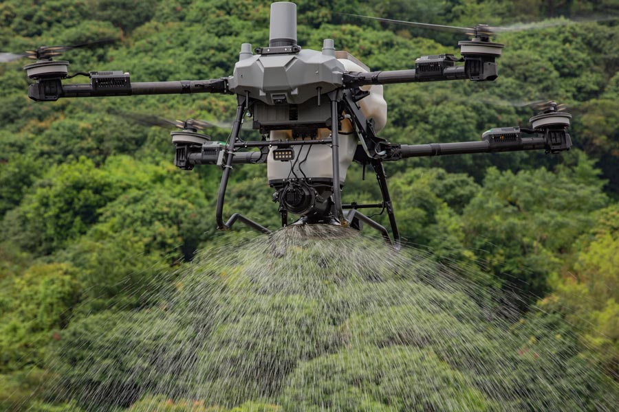 DJI Agras T70P spreading granules over rolling farmland